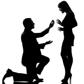 一對白人夫婦跪在地上拍攝訂婚戒指和女人驚喜在白色背景下的工作室剪影