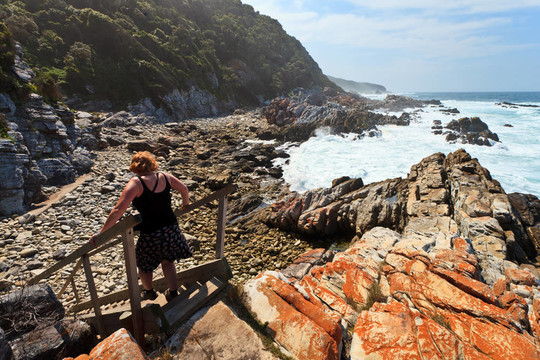 沿著巖石海岸徒步旅行的女子
