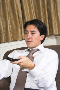 商務(wù)男子在沙發(fā)上用遙控器