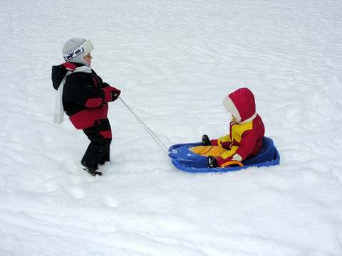 男孩在雪橇上騎嬰兒