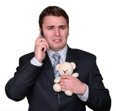 年輕商人在手機(jī)上哭泣，緊緊抓住Teddy Bear。