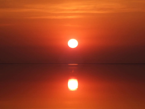在一個(gè)平靜的海灣上空紅色的夕陽(yáng)