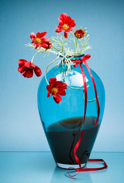 豪華的玻璃花瓶，紅色小花和藍(lán)色緞帶