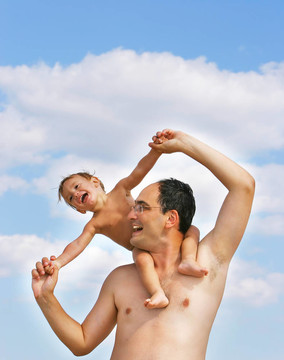 父亲和儿子在海滩上玩天空背景