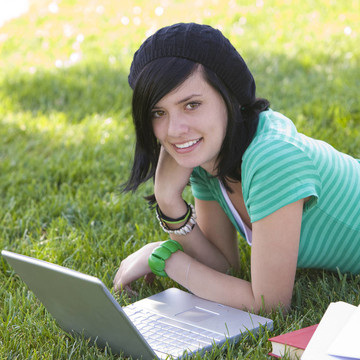 快乐的青少年在草地上与笔记本电脑
