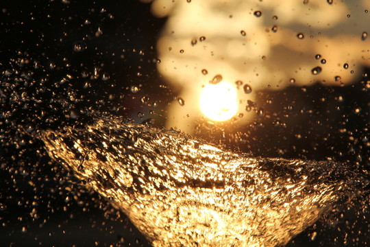 太陽光夕陽下的噴泉水珠背景