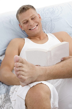 微笑帥哥躺在床上看書