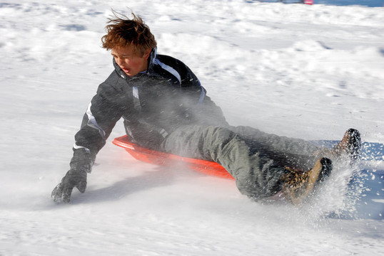 男孩在滑雪下坡制動