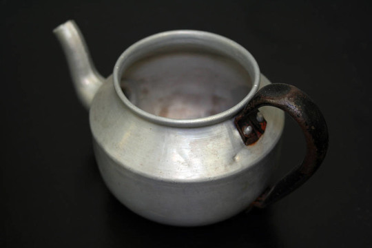 老銹鋁茶壺在黑色的桌子上