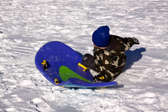 小男孩坐雪橇滑下Hill