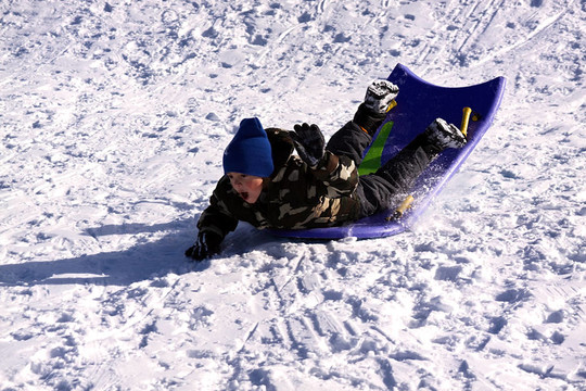 小男孩坐雪橇滑下Hill