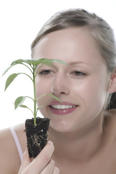 美麗的金發(fā)女孩抱著年輕的植物