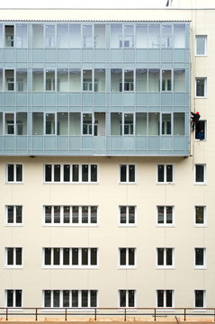 米色立面的建設(shè)與許多窗戶和陽臺建設(shè)。登山家工作的立面上掛線。