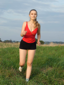 紅色的運動女孩在草地上對抗天空。