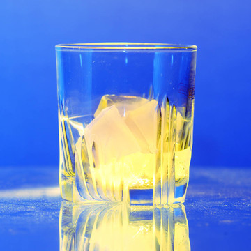 布滿灰塵的桌子上燃燒的冰的威士忌玻璃杯