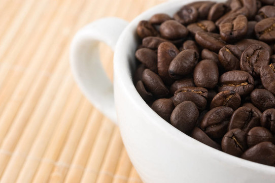 咖啡粒和杯放在竹墊