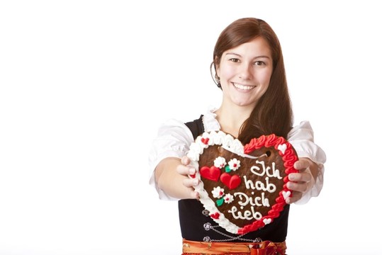 笑在慕尼黑緊身連衣裙的年輕女子抱lebkuchenh