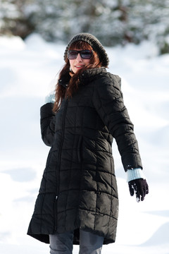 年輕漂亮的女人在冬季服裝投擲雪球