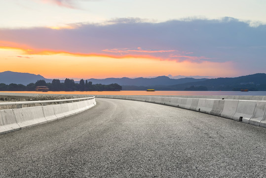 前景是瀝青道路的湖泊晚霞