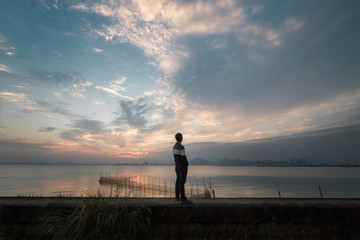 站在海邊眺望夕陽的人