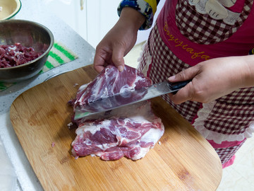 家庭主婦在廚房砧板上切豬肉