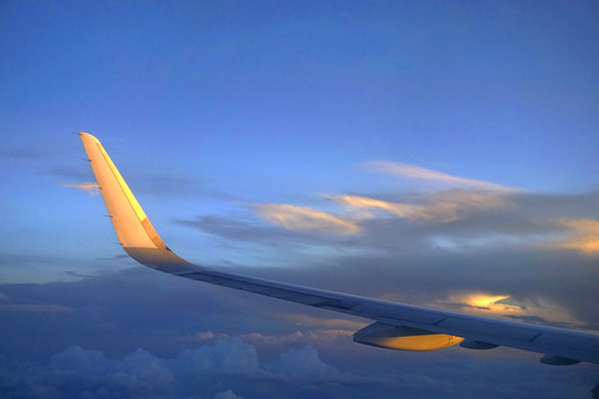 航拍金色云层中的民航客机机翼
