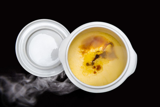 黑背景下陶瓷燉盅里的雞蛋糕美食