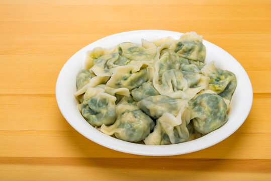 木紋桌面上白色盤子中煮的水餃