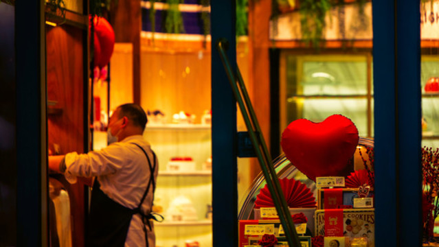 清晨蛋糕店師傅在燈光中整理貨架