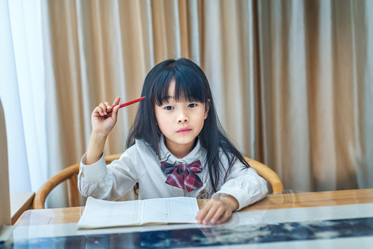 坐在書桌前寫作業(yè)的小女孩