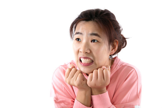 雙拳托下巴驚恐表情的女性