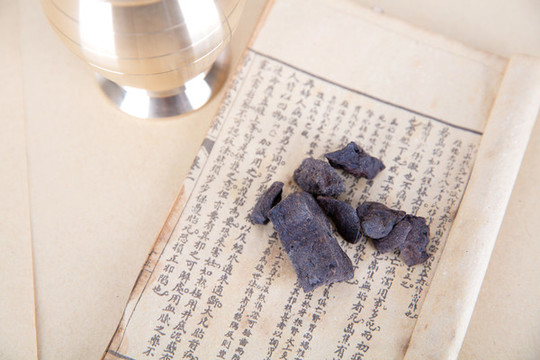 醫(yī)書上的藥材和旁邊的藥杵