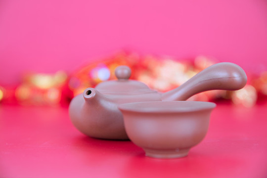 紅背景上的紫砂把壺和茶碗