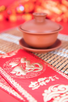 紅背景上的紫砂蓋碗和新年紅包
