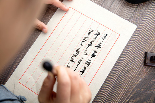 手握毛筆正要在宣紙上寫字的人