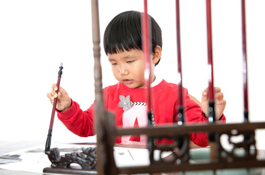 白背景前練習(xí)書法的小女孩