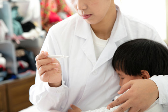 醫(yī)生抱著患病的兒童查看體溫計