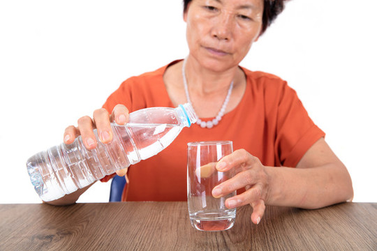 把瓶裝礦泉水倒進(jìn)玻璃杯里