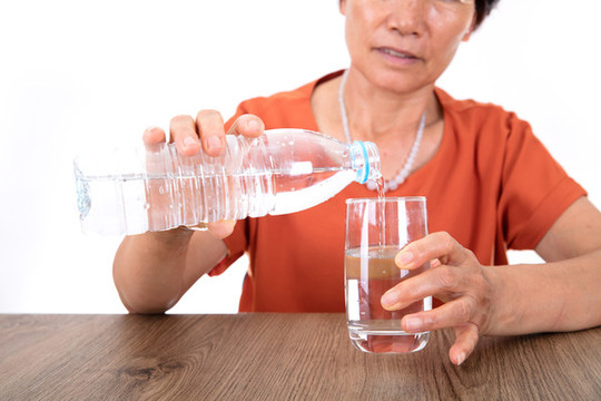 把瓶裝礦泉水倒進(jìn)玻璃杯里
