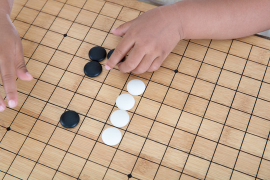 手拿著棋子在圍棋棋盤上下棋