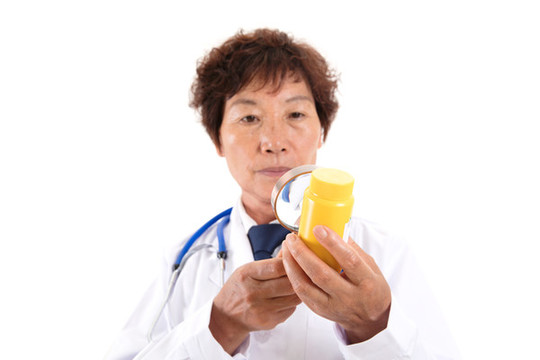 中國老醫(yī)生正拿放大鏡看藥瓶