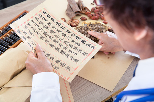 藥房里老中醫(yī)正看著藥方抓藥