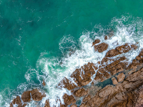 航拍海邊礁石海浪背景圖
