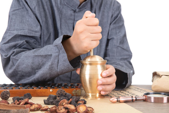 中醫(yī)醫(yī)生正使用藥臼把草藥搗碎
