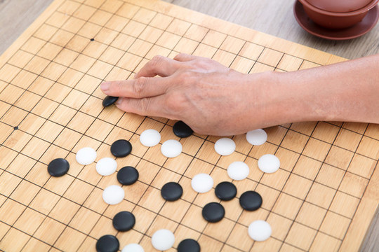 手拿圍棋棋子在棋盤上落子