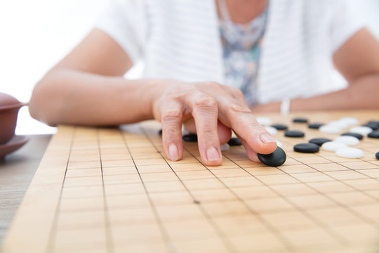 手拿黑色棋子在圍棋棋盤上落子