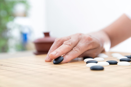 手拿黑色棋子在圍棋棋盤上落子