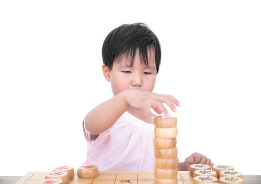 小女孩桌子上摞中國(guó)象棋棋子