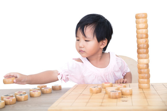 小女孩桌子上摞中國象棋棋子