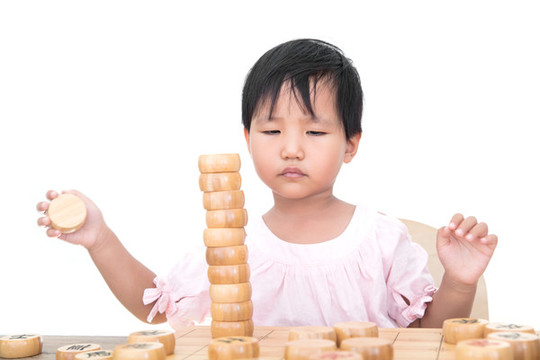 小女孩桌子上摞中國象棋棋子